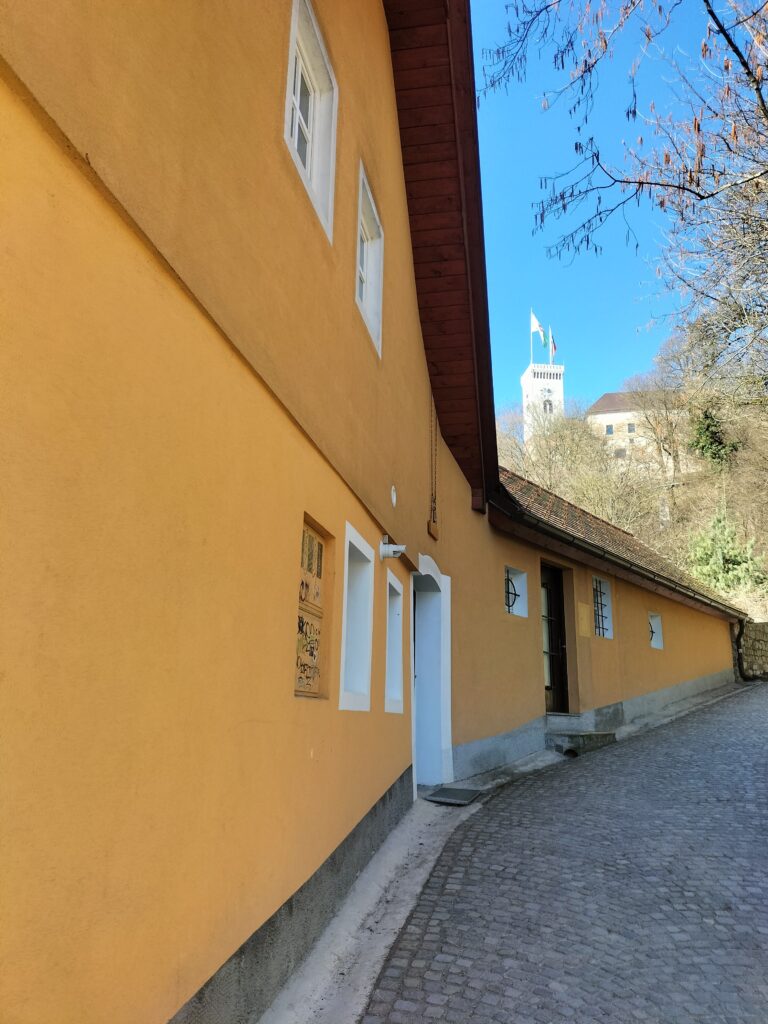 Bâtiments jaunes, ruelle pavée et vue sur le château de Ljubljana